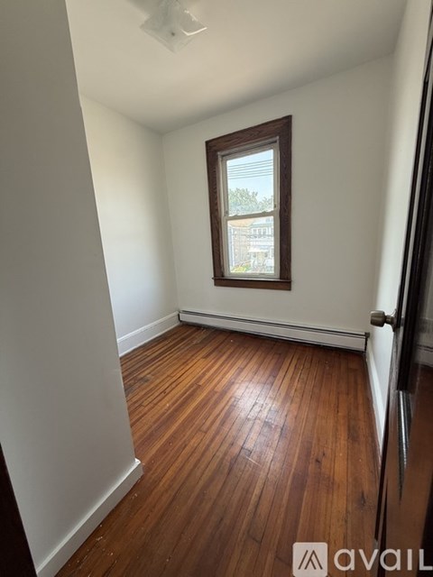 A room with wooden floors and a window showing a view of a building.