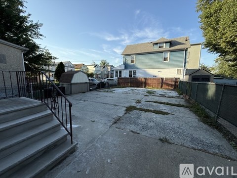 A backyard with a concrete patio and a metal railing.