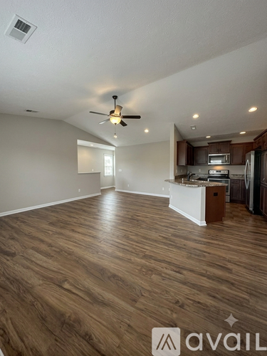 A spacious kitchen and living room with wood flooring and a ceiling fan.
