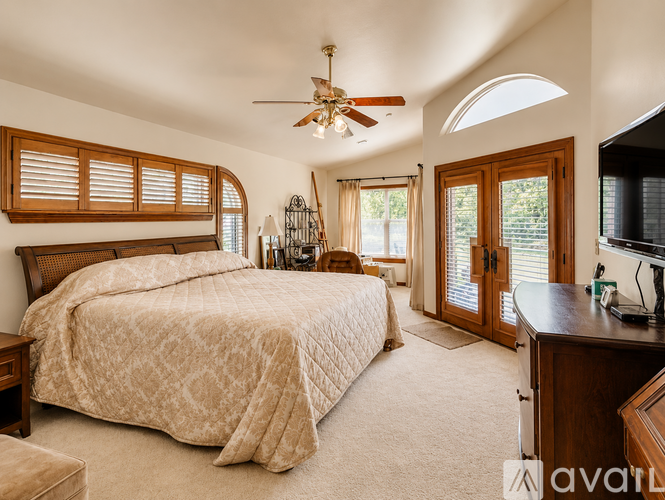 A bedroom with a large bed and a ceiling fan.