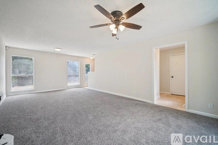 A spacious room with a ceiling fan and carpeted floor.
