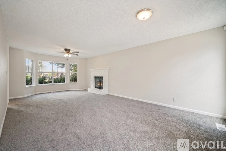 A spacious living room with a fireplace and a ceiling fan.