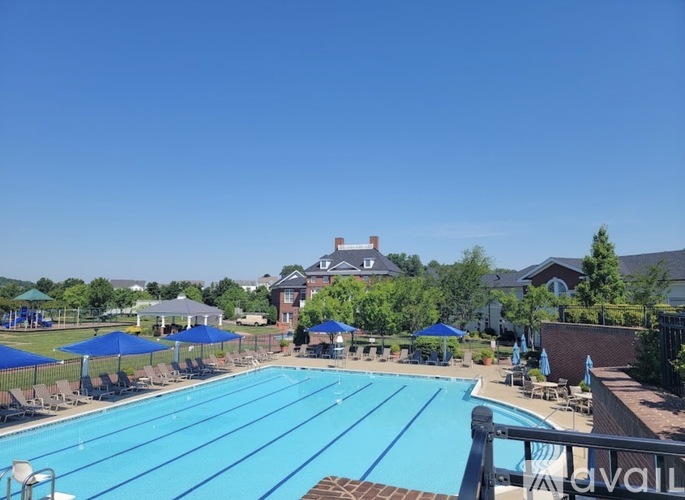 A large blue swimming pool surrounded by lawn chairs and umbrellas.