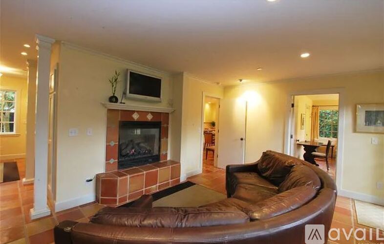 A living room with a brown leather couch and a brick fireplace.