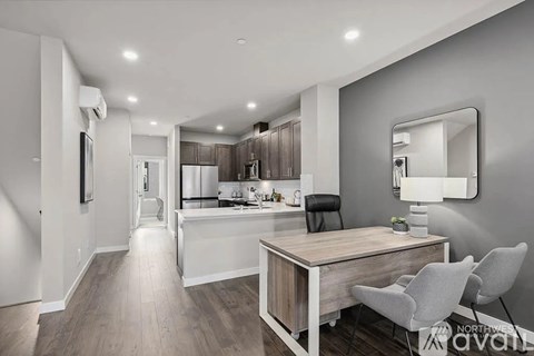 A modern kitchen with a desk and chairs in the foreground.