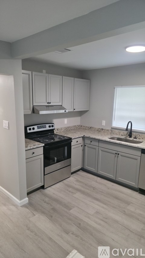 A kitchen with a stove top oven, sink, and cabinets.