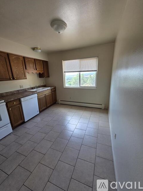A kitchen with tile flooring and wooden cabinets.
