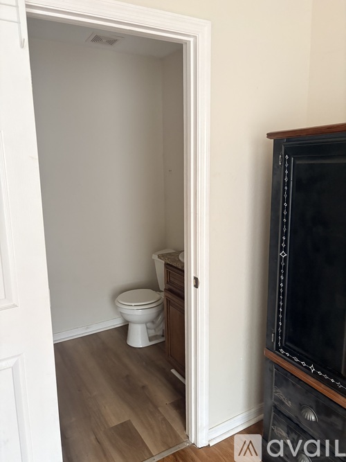 A bathroom with a toilet and a doorway leading to a living room.