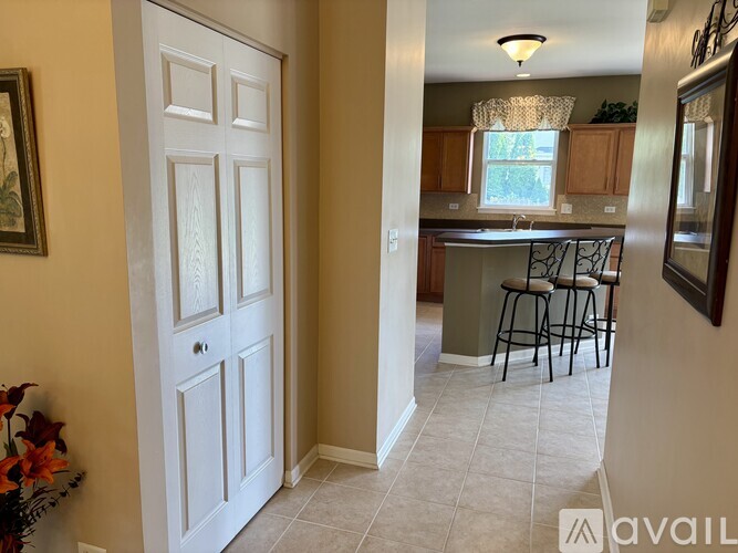 A white door is in a hallway leading to a kitchen.