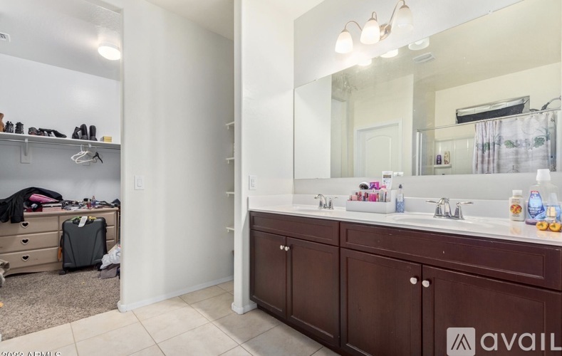 A bathroom with a large mirror, double sinks and a wooden cabinet.