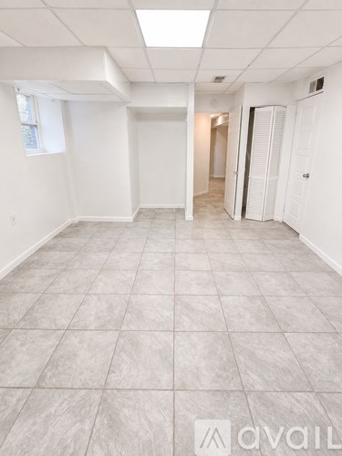A spacious room with tiled flooring and white walls.
