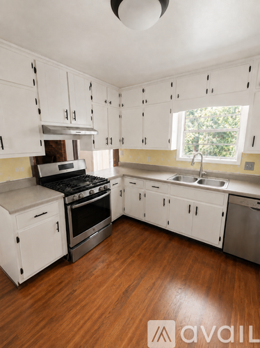 A kitchen with white cabinets and a wooden floor.