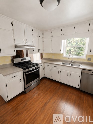A kitchen with white cabinets and a wooden floor.