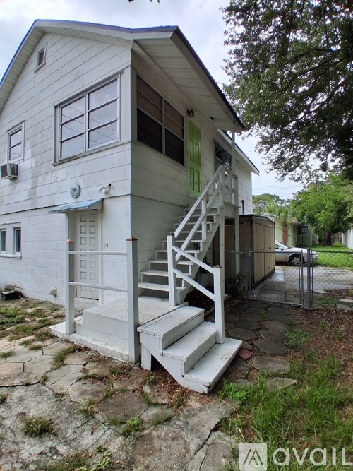 A white house with a staircase leading to the front door.