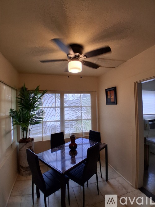 A dining room with a table and chairs and a ceiling fan.