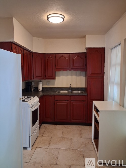 A kitchen with red cabinets and a white refrigerator.