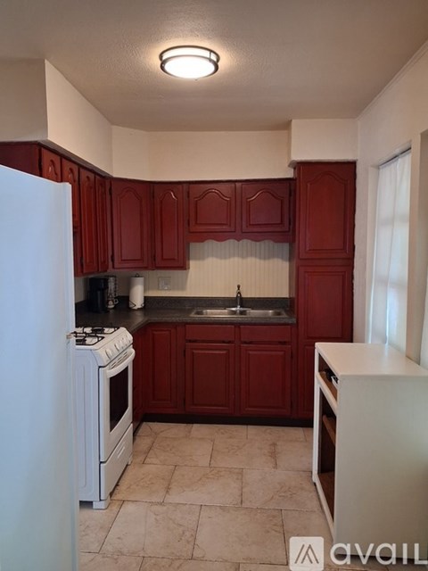 A kitchen with red cabinets and a white refrigerator.