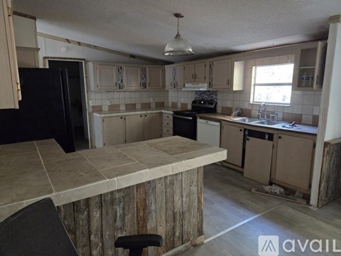 A kitchen with a black fridge and a wooden island.