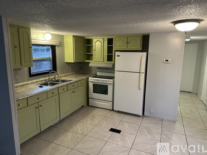A kitchen with green cabinets and a white refrigerator.