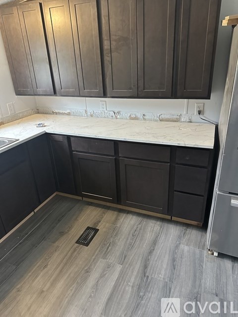 A kitchen with dark wood cabinets and a white countertop.