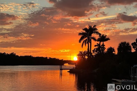 A beautiful sunset over a body of water with palm trees in the foreground.