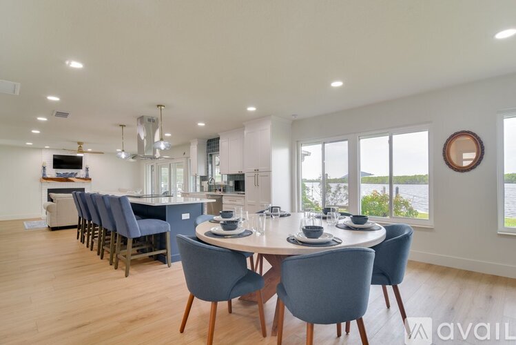A dining room with a table set for six and a view of the water outside the window.