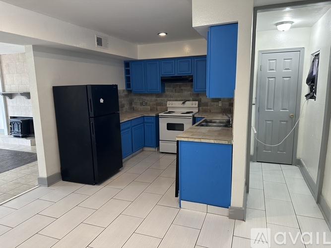 A kitchen with blue cabinets and a black fridge.