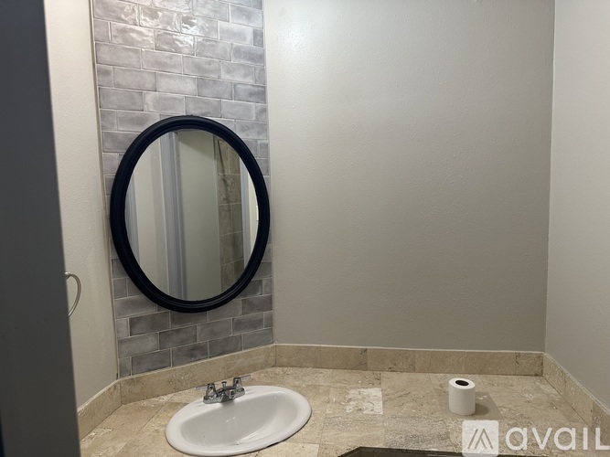 A bathroom with a marble sink and a round mirror.