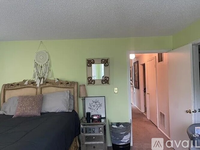 A bedroom with a bed, nightstand, and a dream catcher hanging on the wall.