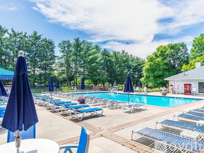 A pool area with sun loungers and umbrellas.