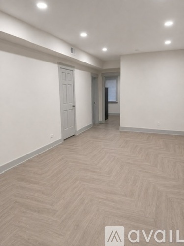A spacious room with a herringbone patterned floor and white walls.