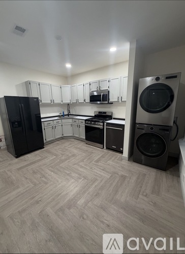 A kitchen with black appliances and wooden flooring.