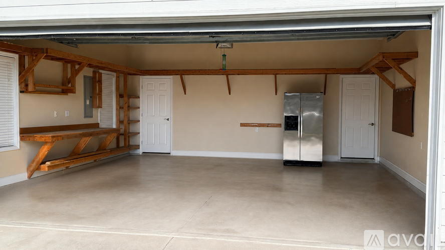 A spacious garage with a refrigerator and a bench.