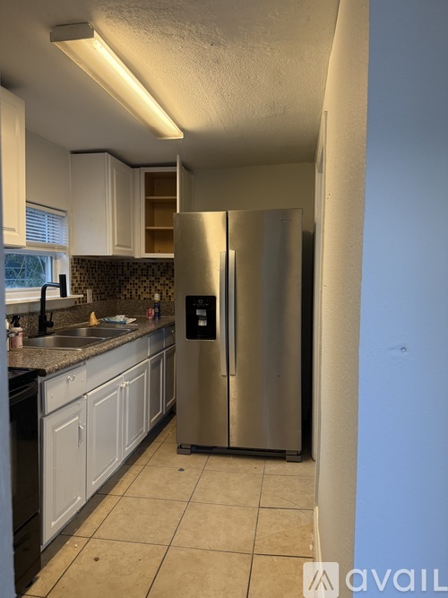 A kitchen with a stainless steel refrigerator and black appliances.