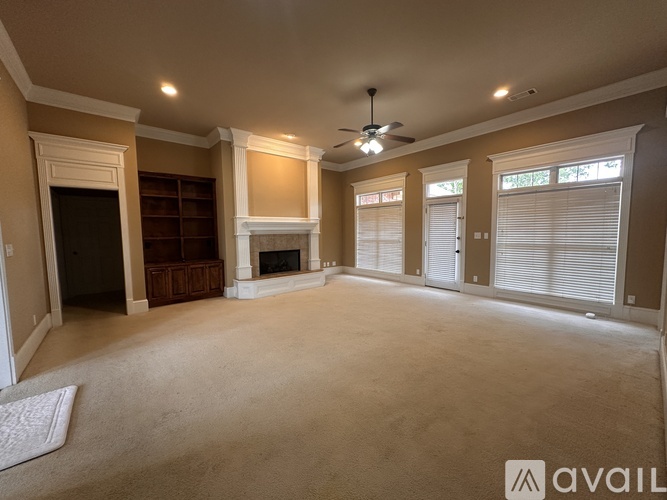 A spacious living room with a fireplace and a ceiling fan.
