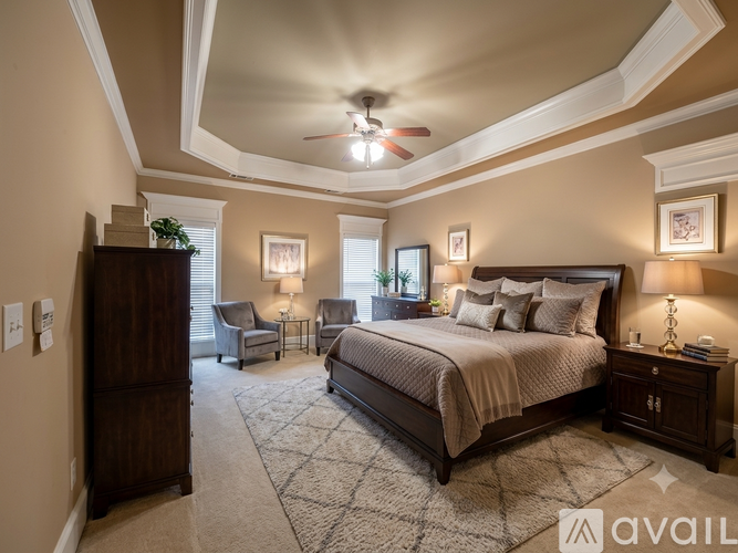 A bedroom with a large bed, a ceiling fan, and a chair.