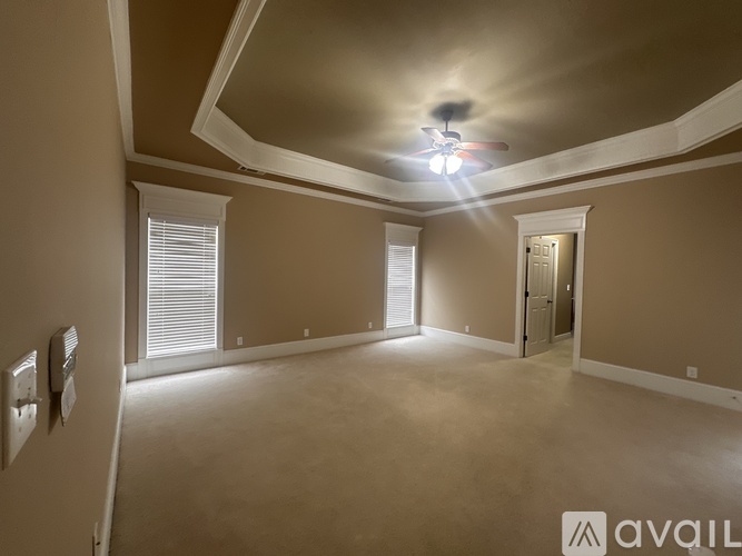A spacious room with a ceiling fan and three windows.
