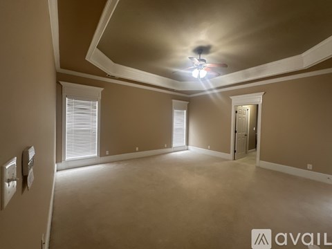 A spacious room with a ceiling fan and three windows.