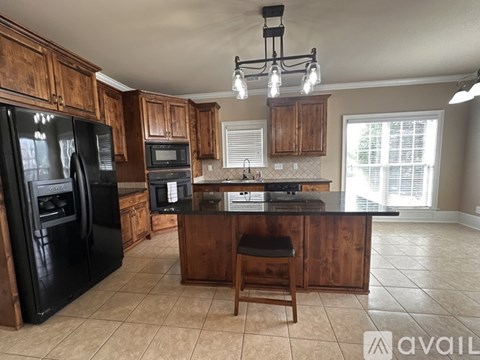 A kitchen with wooden cabinets and a black refrigerator.