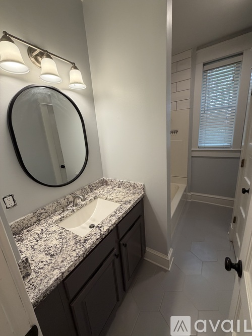 A bathroom with a marble countertop and a round mirror.