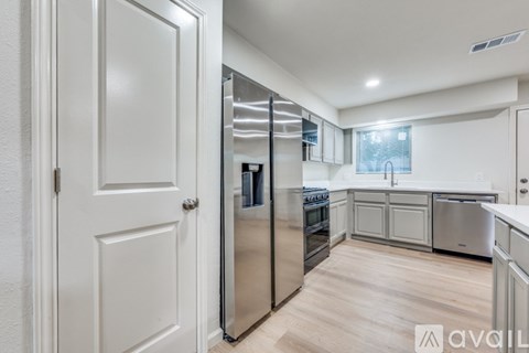 A kitchen with white cabinets and a stainless steel refrigerator.