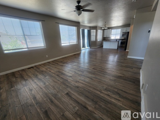 A spacious room with wooden flooring and a ceiling fan.