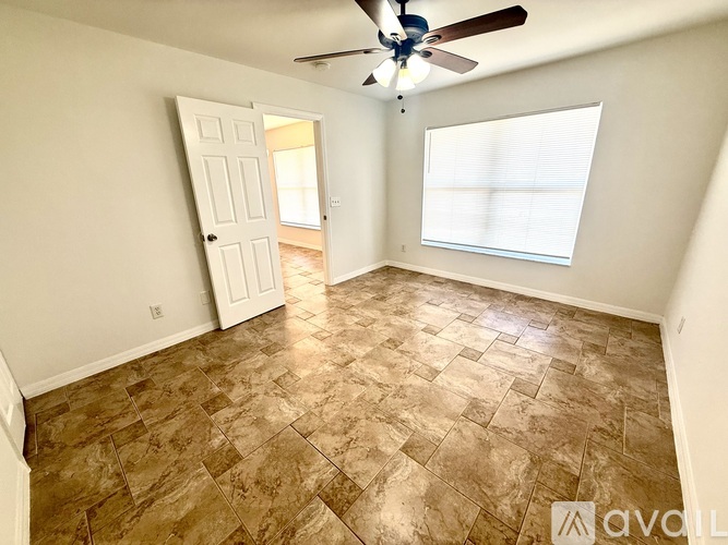 A room with a ceiling fan and tile flooring.