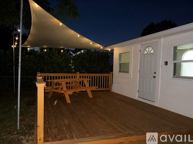 A wooden deck with a white canopy and a bench.