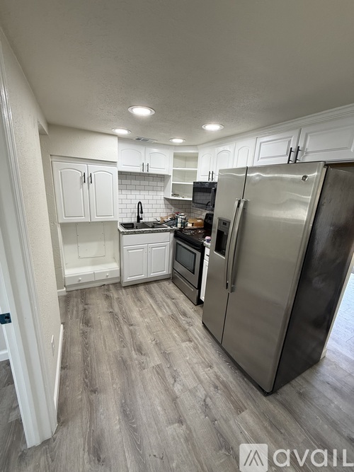 A kitchen with a refrigerator, microwave, and oven.