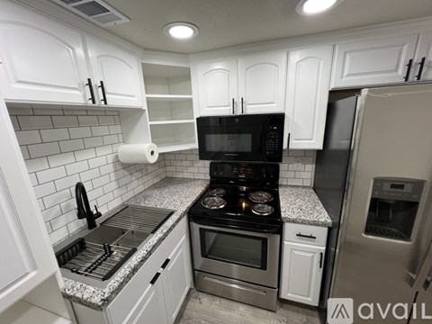 A kitchen with white cabinets and a granite countertop.