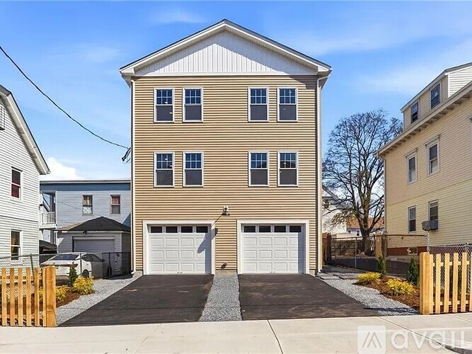 A two-story house with a garage is surrounded by a wooden fence.