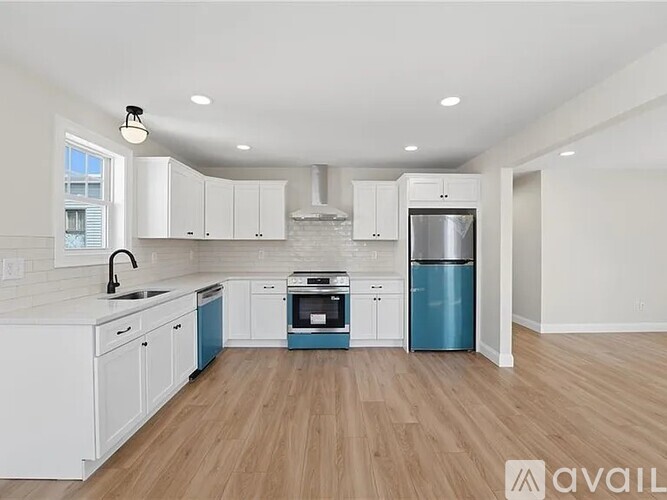 A kitchen with white cabinets and a blue trash can.