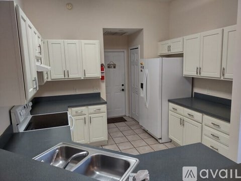 A kitchen with white cabinets and a black countertop.