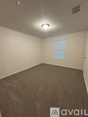 A room with a carpeted floor and a window with blinds.